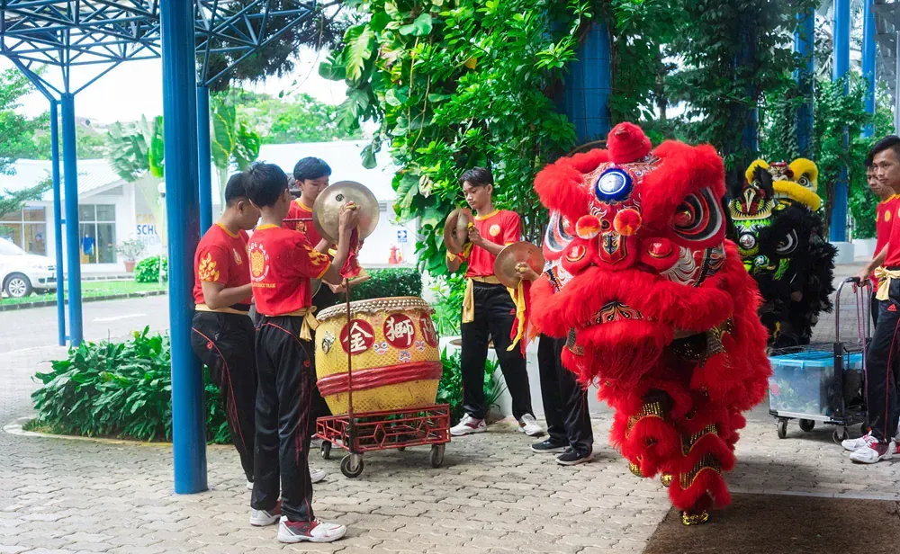 A group of men are playing drums and a lion is dancing in front of them.