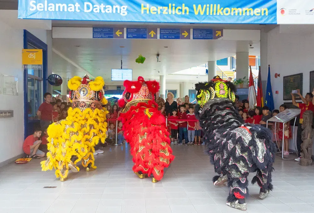 Two lion dancers are performing in front of a sign that says selamat datang