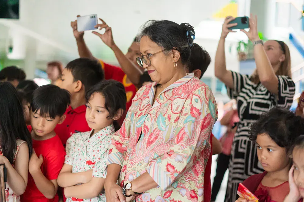 A woman is taking a picture of a group of children.