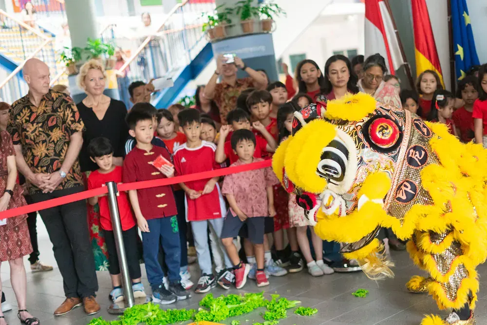 A group of children are watching a lion dancing in front of them.