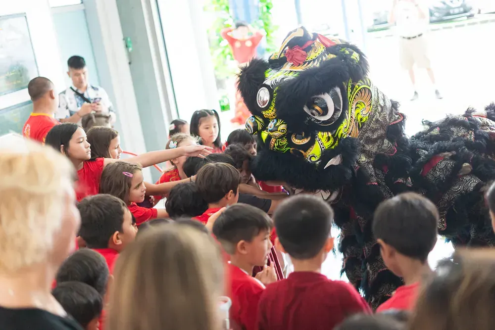 A group of children are watching a lion dance.
