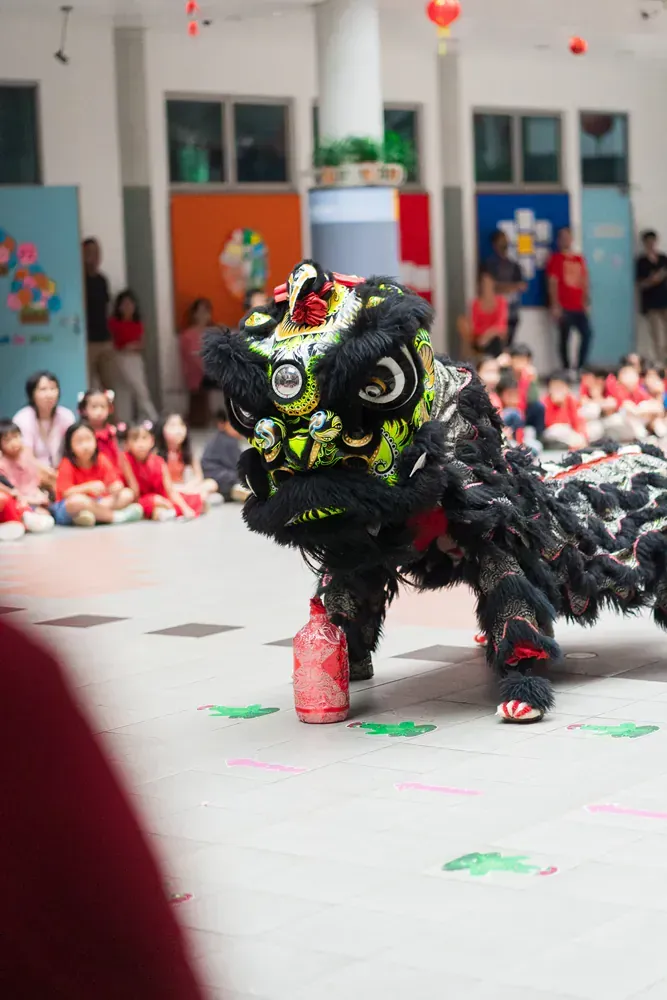 A lion is dancing in front of a crowd of children.