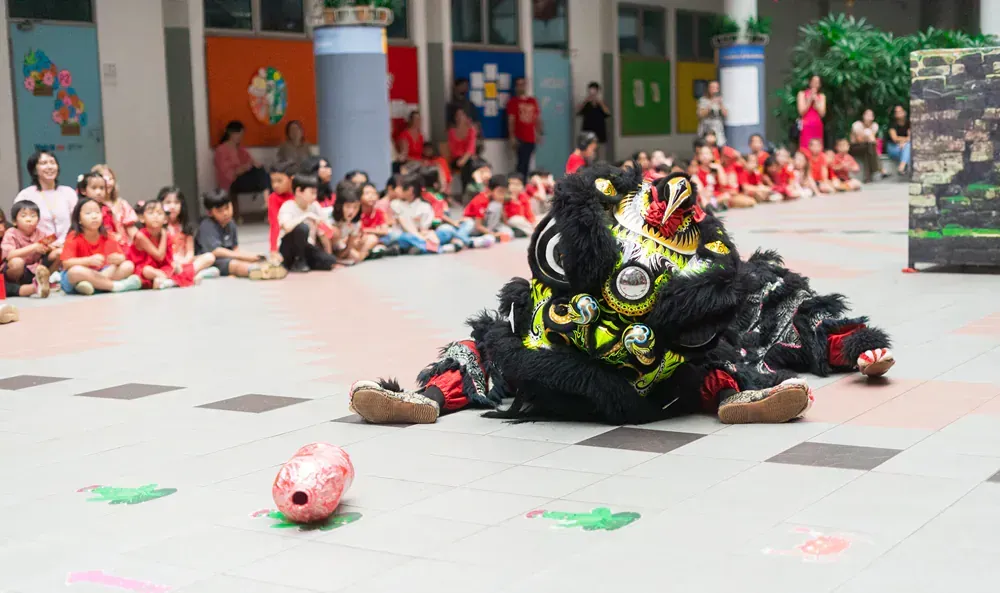 A lion dancing in front of a crowd of children.