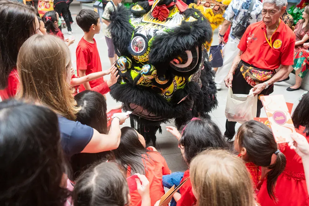 A group of people are standing around a lion costume.