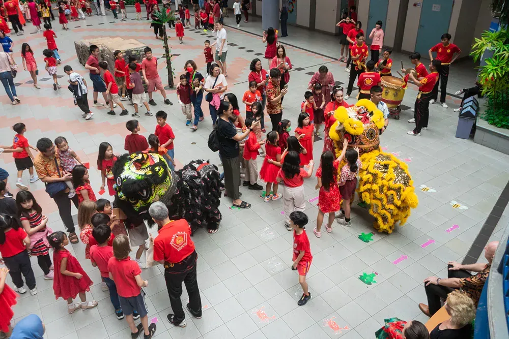 A large group of people are standing around a lion.