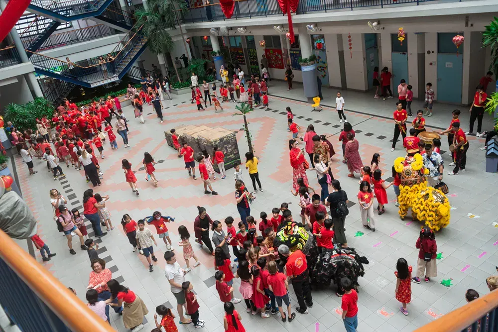 A large group of people in red shirts are dancing in a courtyard.