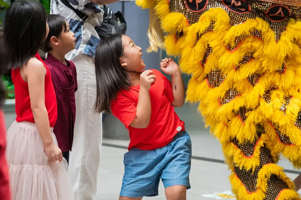 A group of children are standing in front of a lion costume.