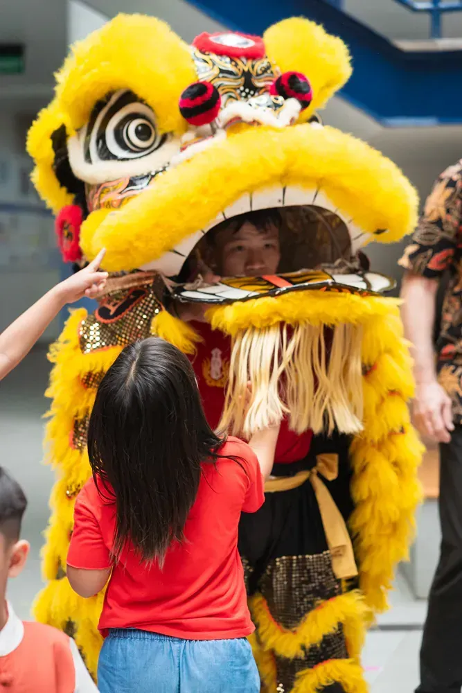 A little girl is petting a lion costume.