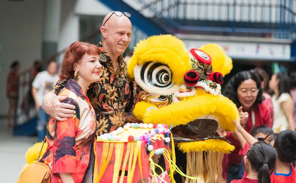 A man and woman are posing for a picture with a lion costume.