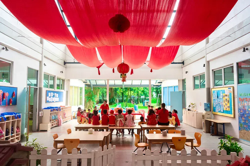 A group of children are sitting at tables in a classroom.