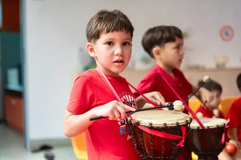 A group of young boys are playing drums in a classroom.