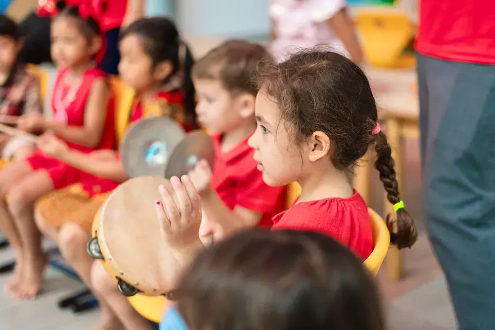 A group of children are sitting in chairs playing instruments.