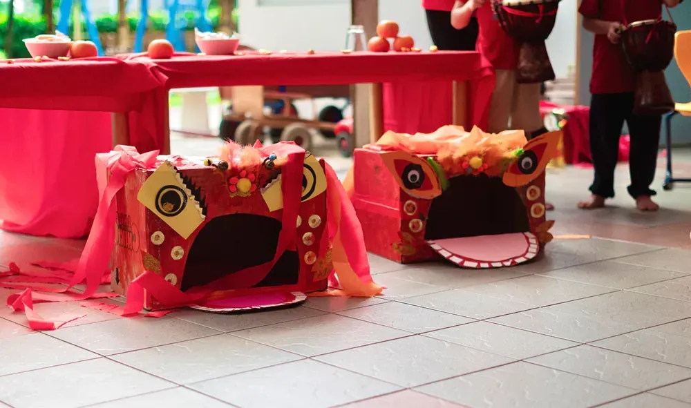 Two lion heads made out of cardboard are sitting on a tiled floor.