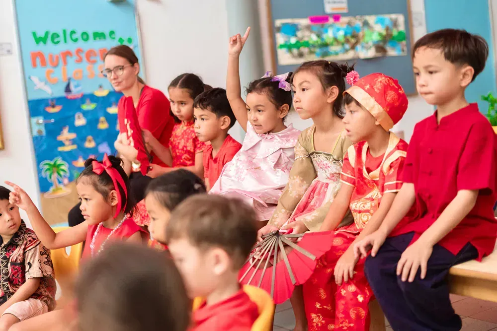 A group of children in red clothes are sitting in a classroom.