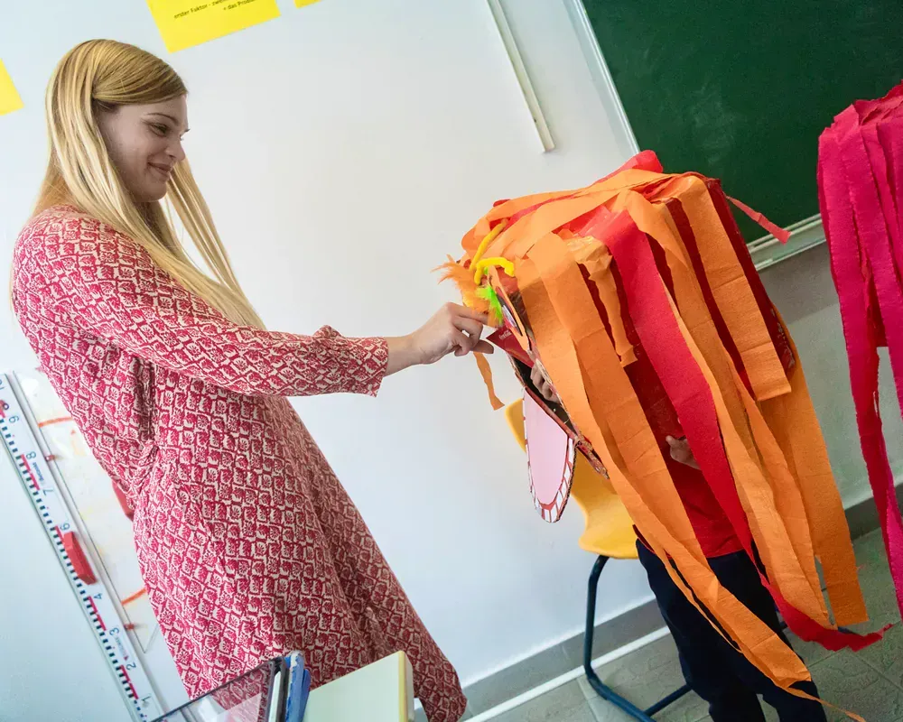 A woman in a red dress is standing next to a child in an orange costume