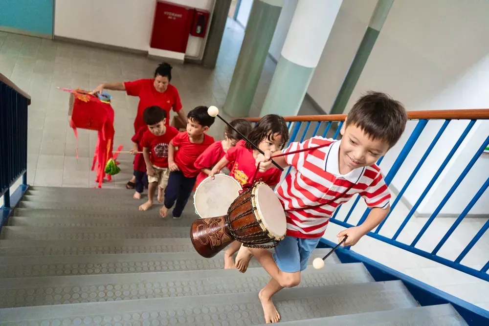 A group of children are playing drums on the stairs.