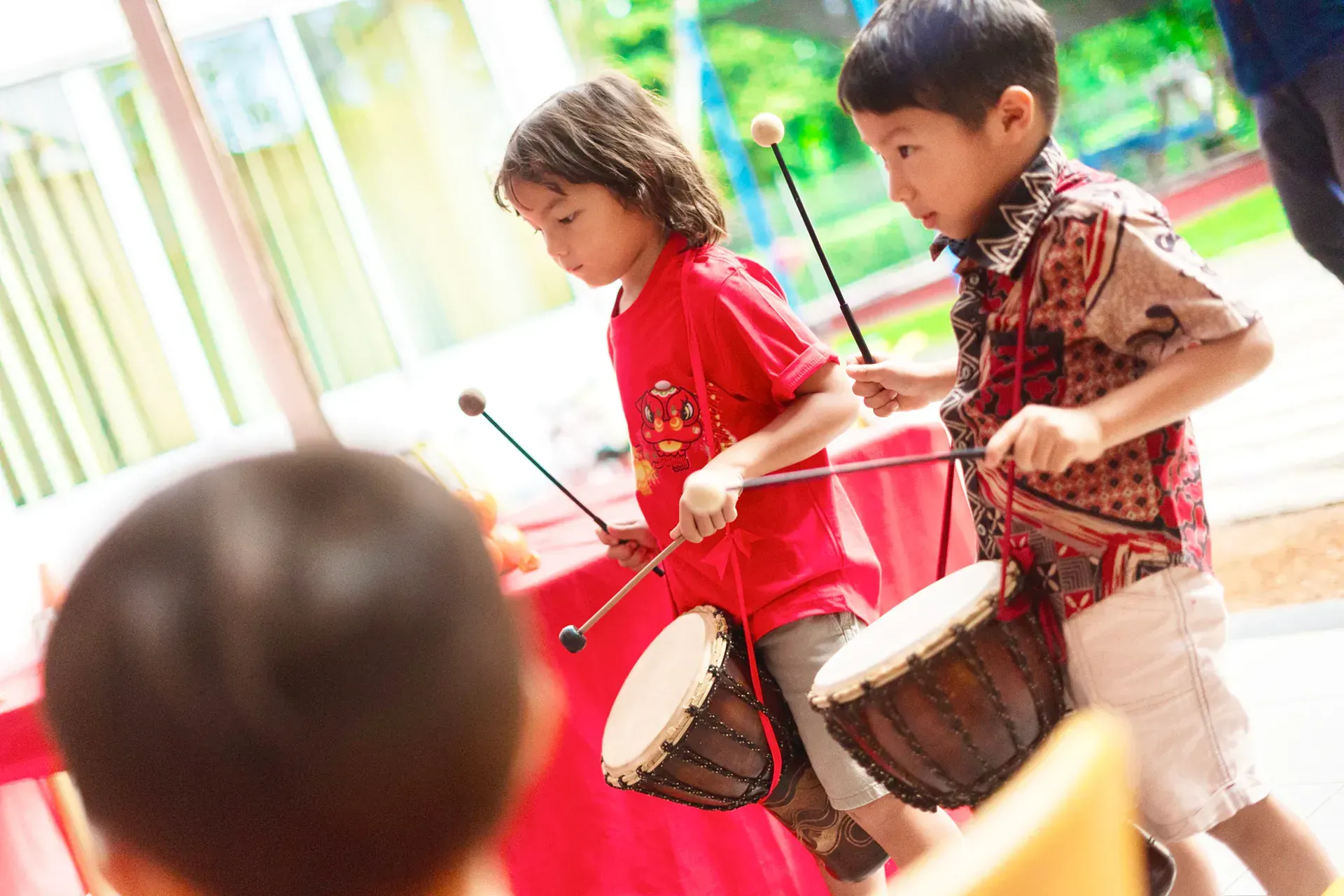 Two young boys are playing drums in a room.