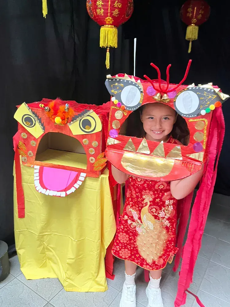 A little girl in a red dress is holding a lion head