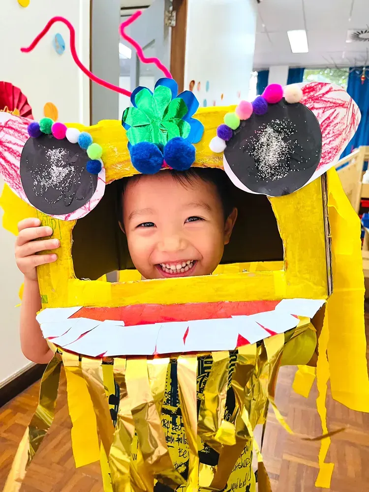 A young boy is wearing a cardboard dragon costume.