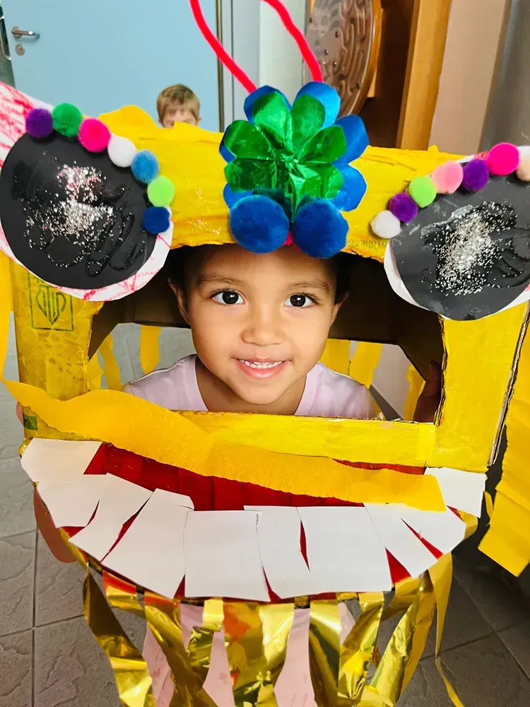 A little girl is wearing a cardboard dragon costume.