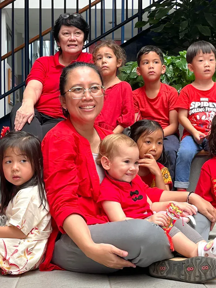 A woman is sitting on the ground with a group of children.