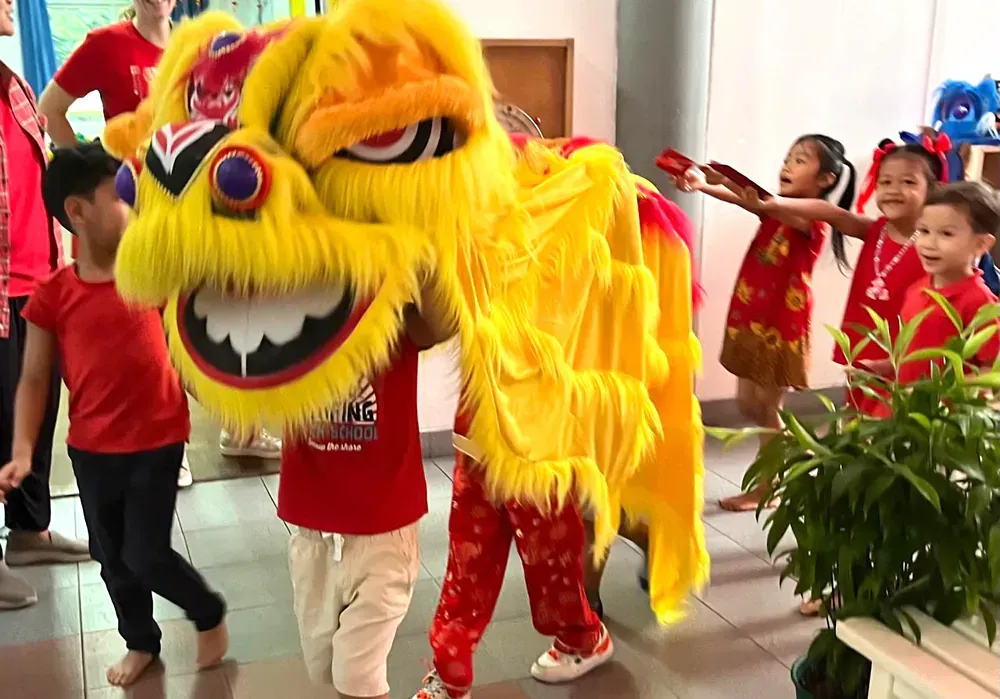 A group of children are standing around a yellow lion costume.