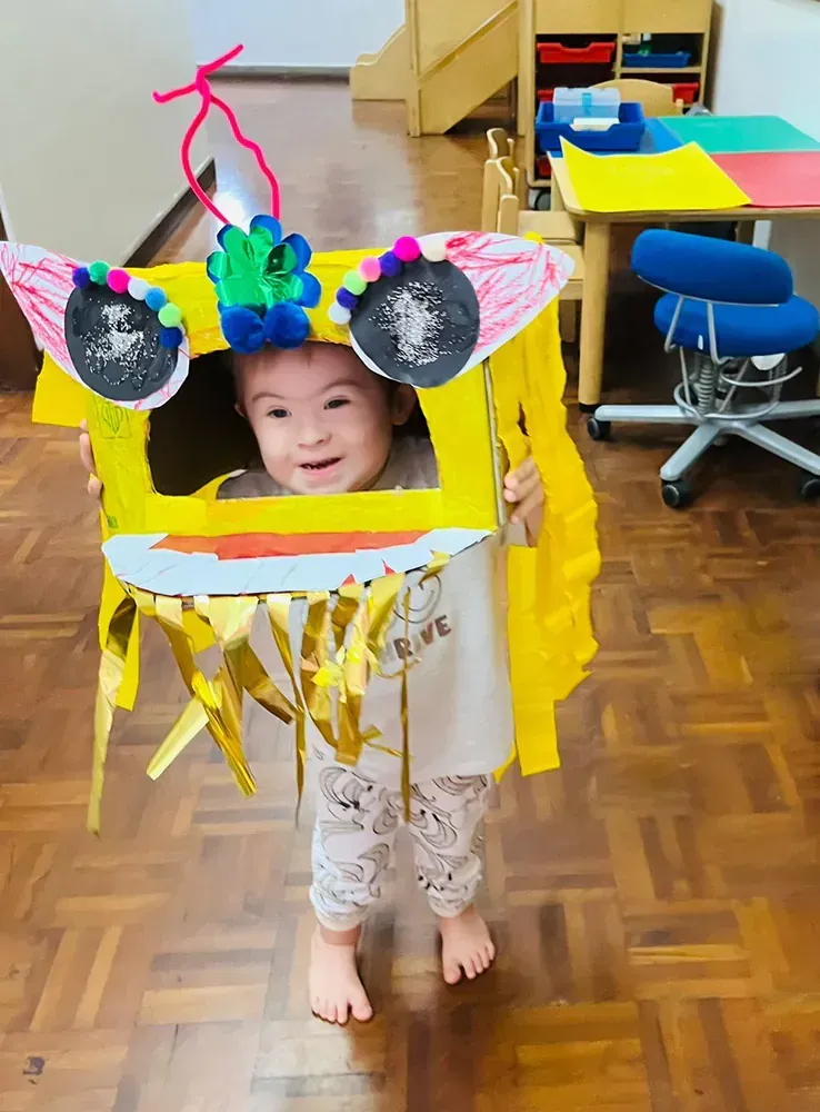 A little girl is wearing a costume made out of a cardboard box.