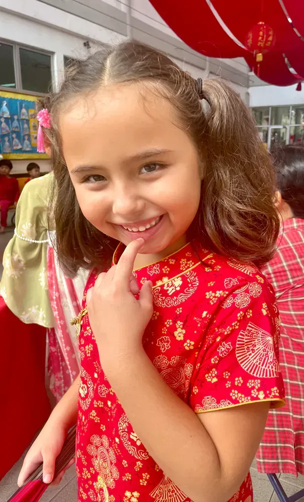 A little girl in a red dress is smiling for the camera.