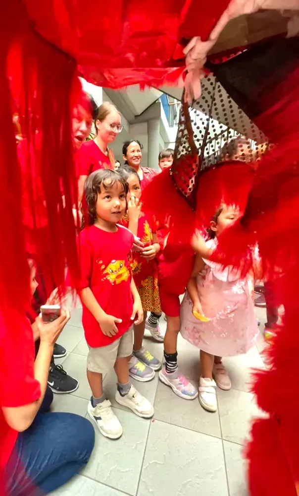 A group of children are standing in front of a red costume.