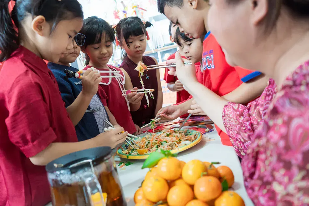 A group of children are sitting at a table eating food with chopsticks.
