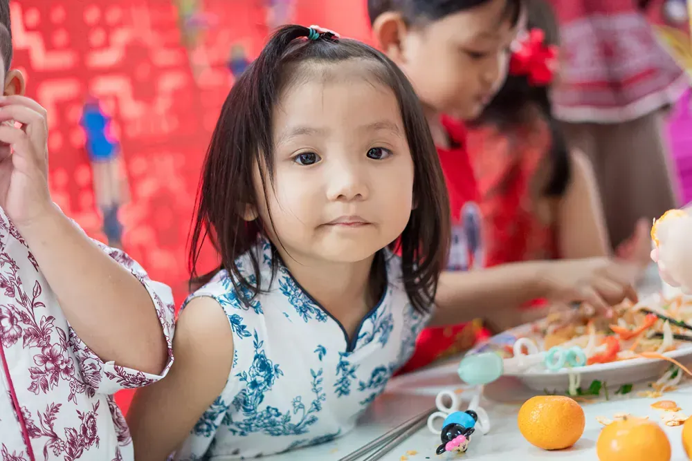 A little girl is sitting at a table with a plate of food.