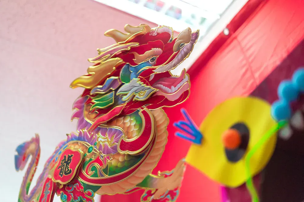 A colorful dragon is sitting in front of a red wall.