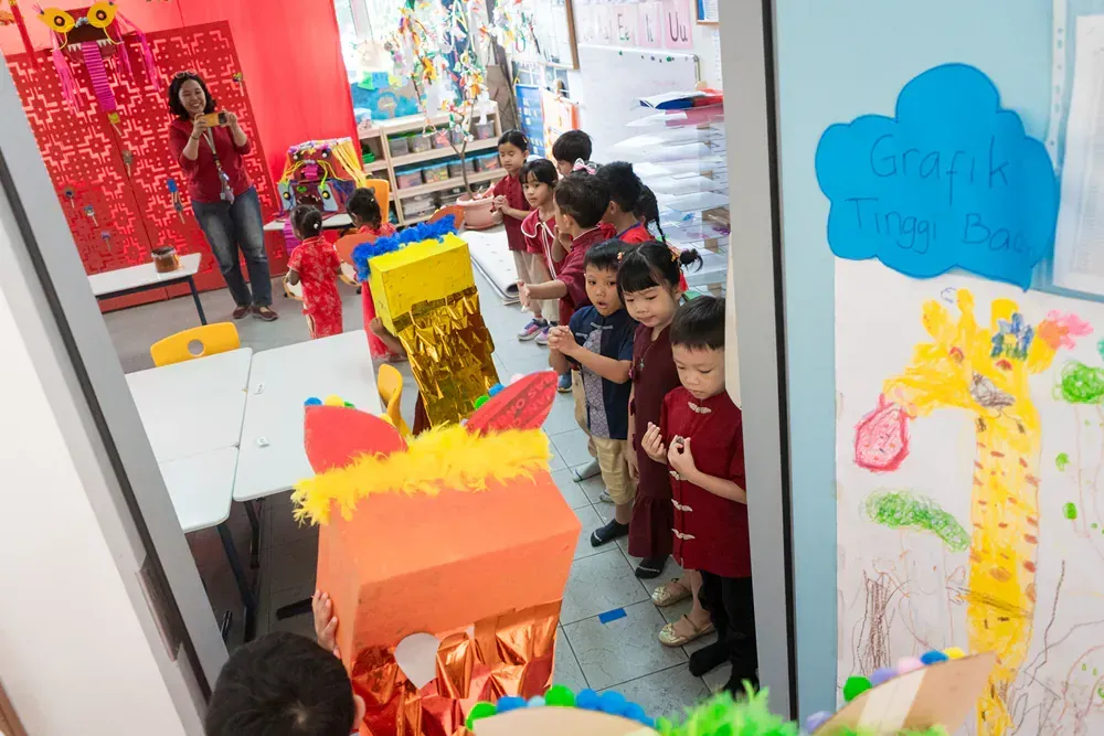 A group of children are standing in a classroom with a teacher.