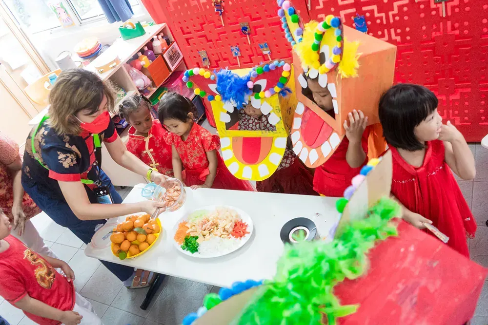 A group of children are sitting at a table with plates of food.