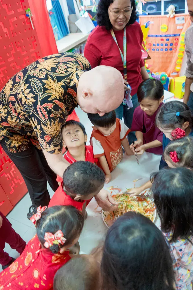 A group of children are gathered around a table eating food.