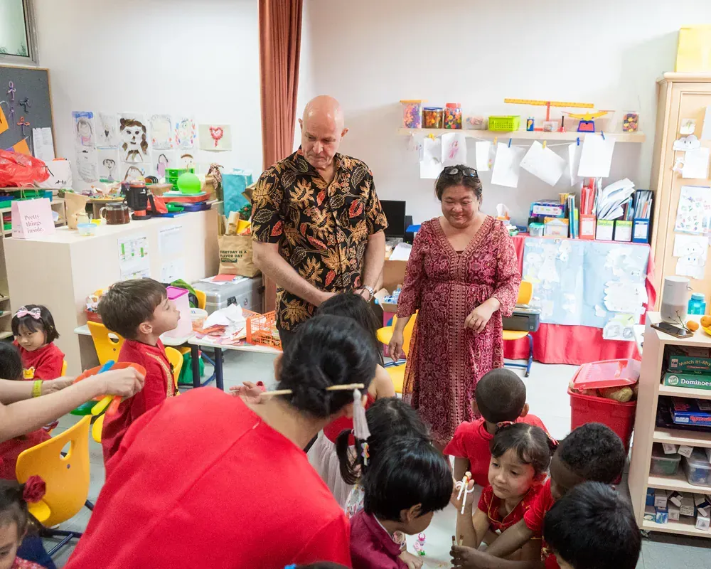 A group of people are standing in a classroom with children.