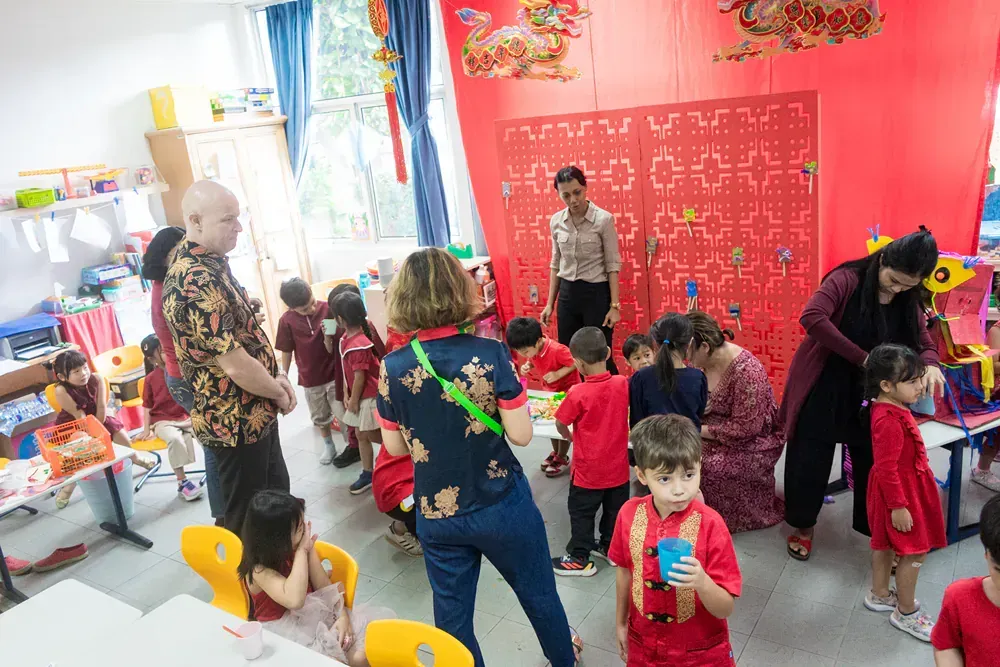 A group of people are standing in a classroom with children.
