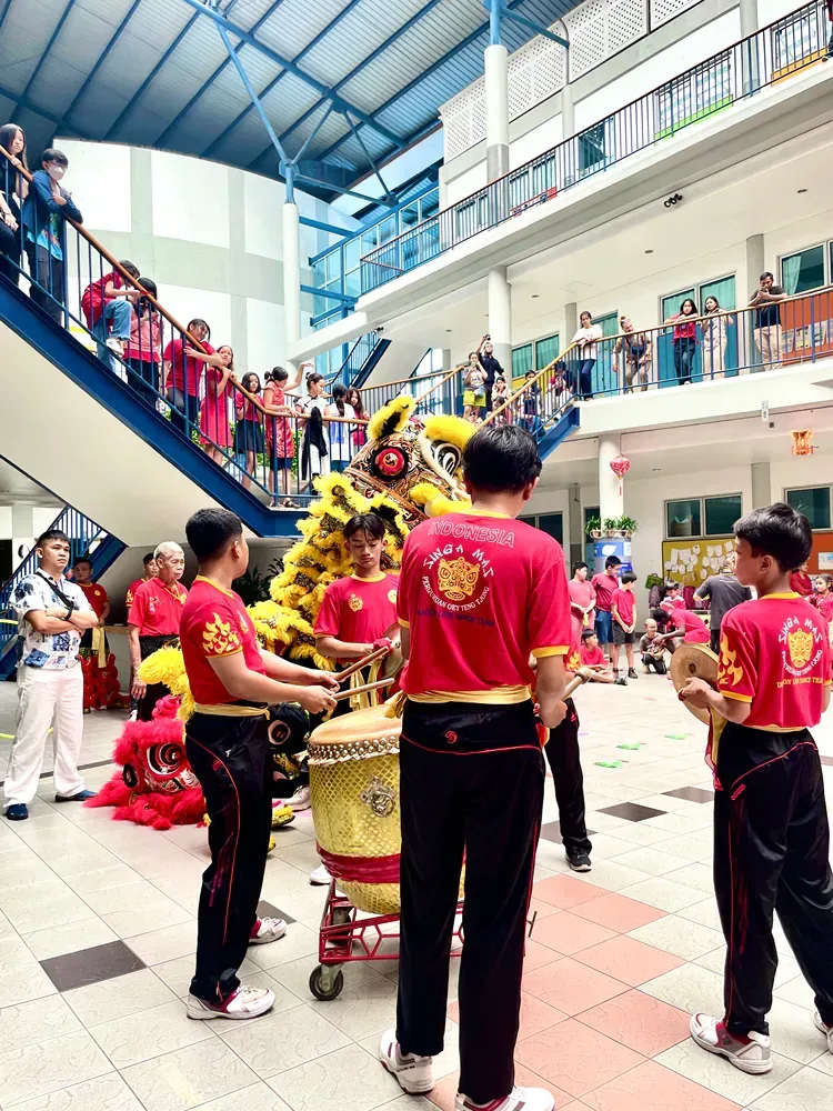 A group of people are standing in front of a lion in a building.