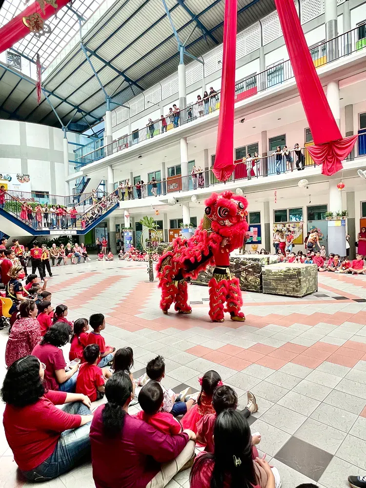 A group of people are sitting on the floor watching a lion dance.