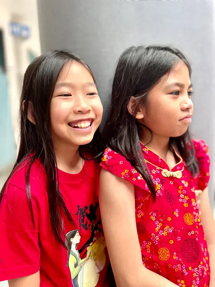Two young girls are standing next to each other and smiling.
