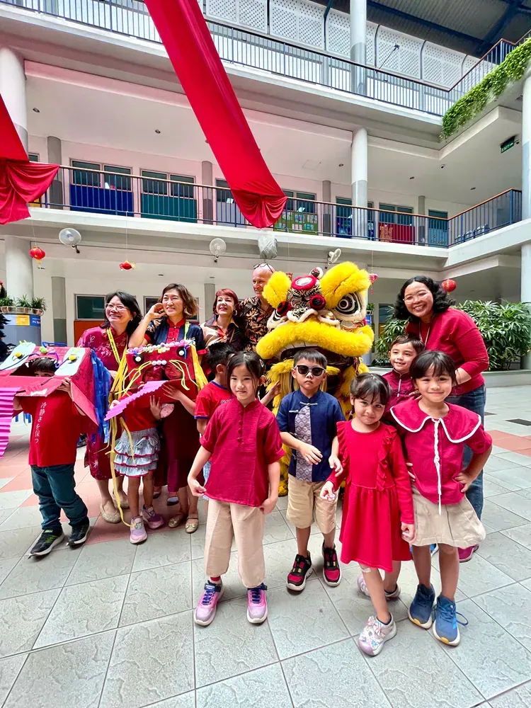 A group of children are posing for a picture in front of a lion costume.