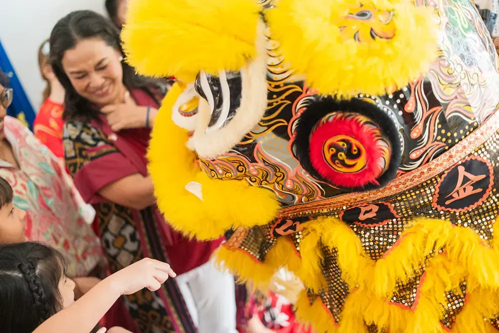 A group of people are standing around a lion costume.