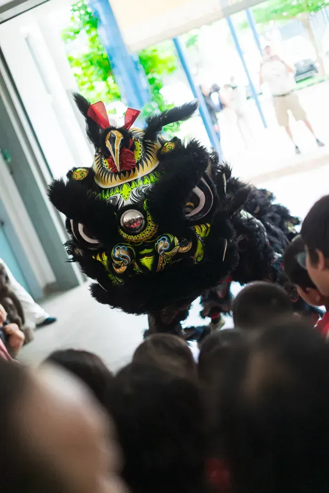A lion is dancing in front of a crowd of people.