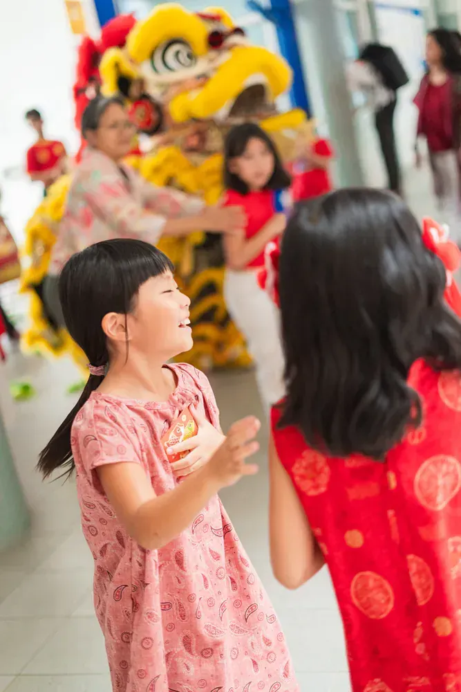 Two little girls are dancing in front of a lion costume.