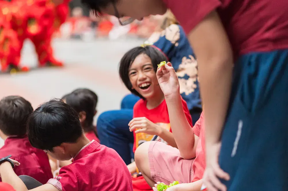 A group of children are sitting on the ground watching a parade.