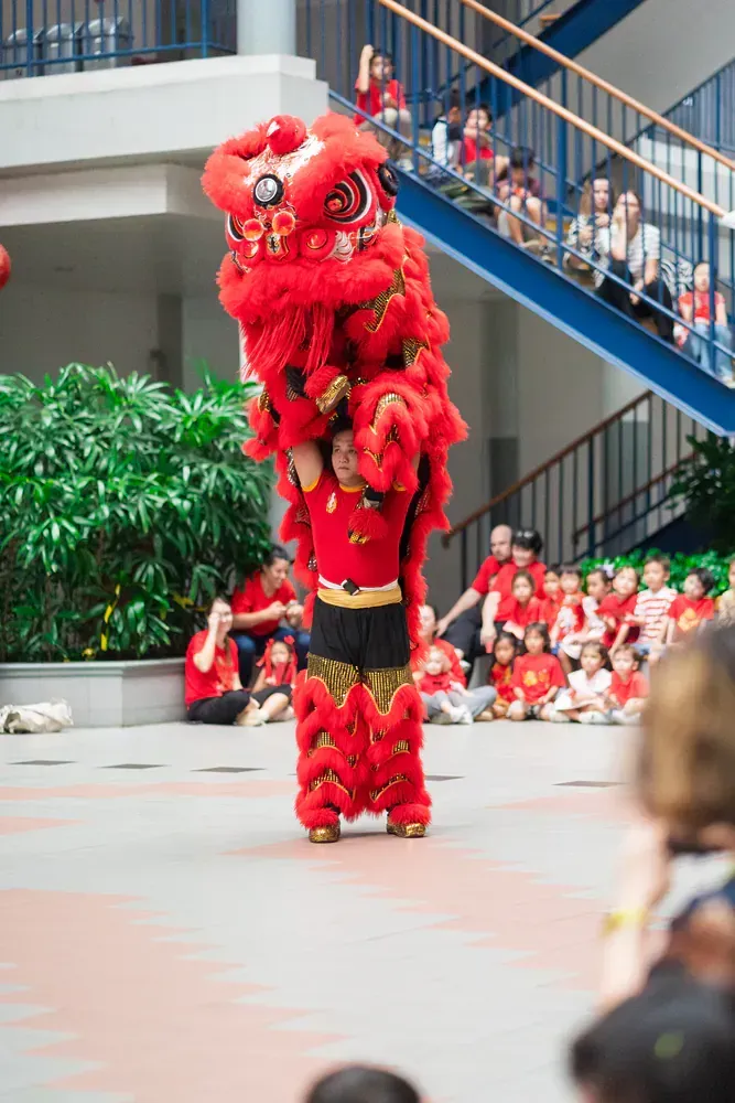 A person is standing on top of a red lion costume.