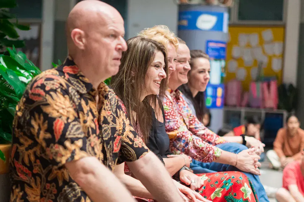 A group of people are sitting in a row and smiling.