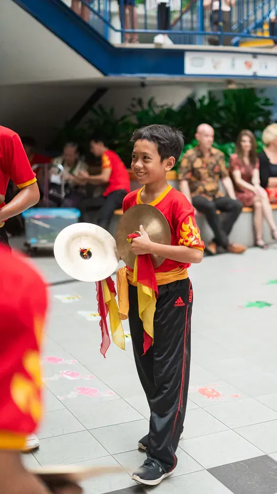 A young boy is holding a cymbal and a megaphone.
