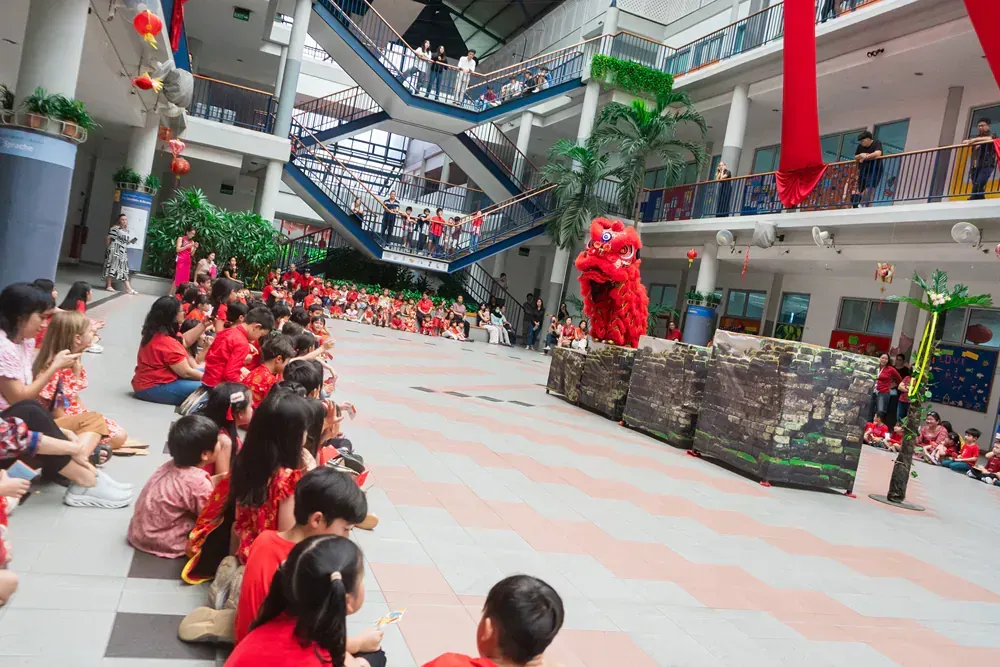 A group of children are sitting on the floor watching a lion display.