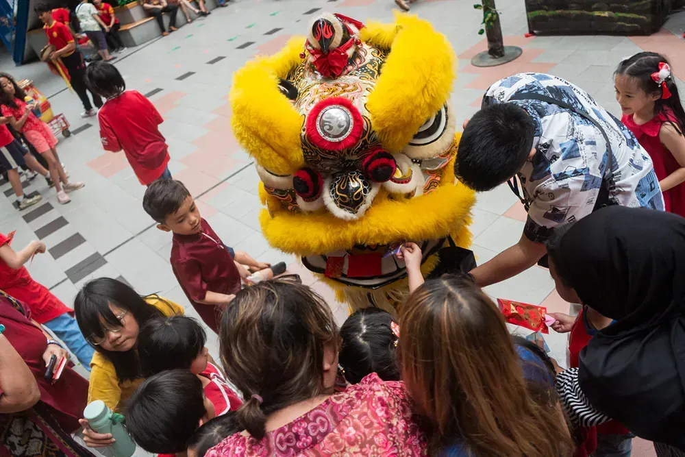 A group of people are standing around a lion costume.